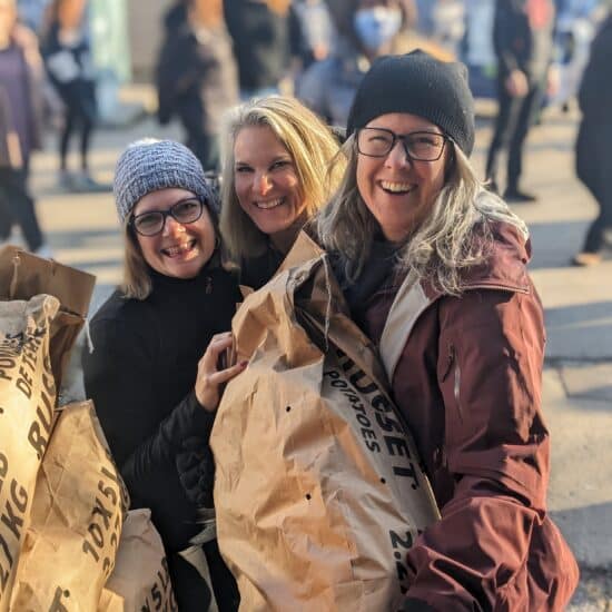 3 women smiling while volunteering to pack resources